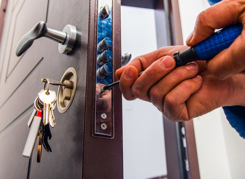 Locksmith Services working on a door lock with keys hanging in the keyhole.
